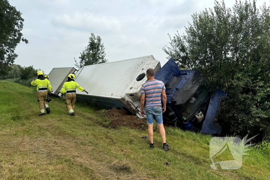 Vrachtwagen belandt in sloot naast snelweg, chauffeur ongedeerd