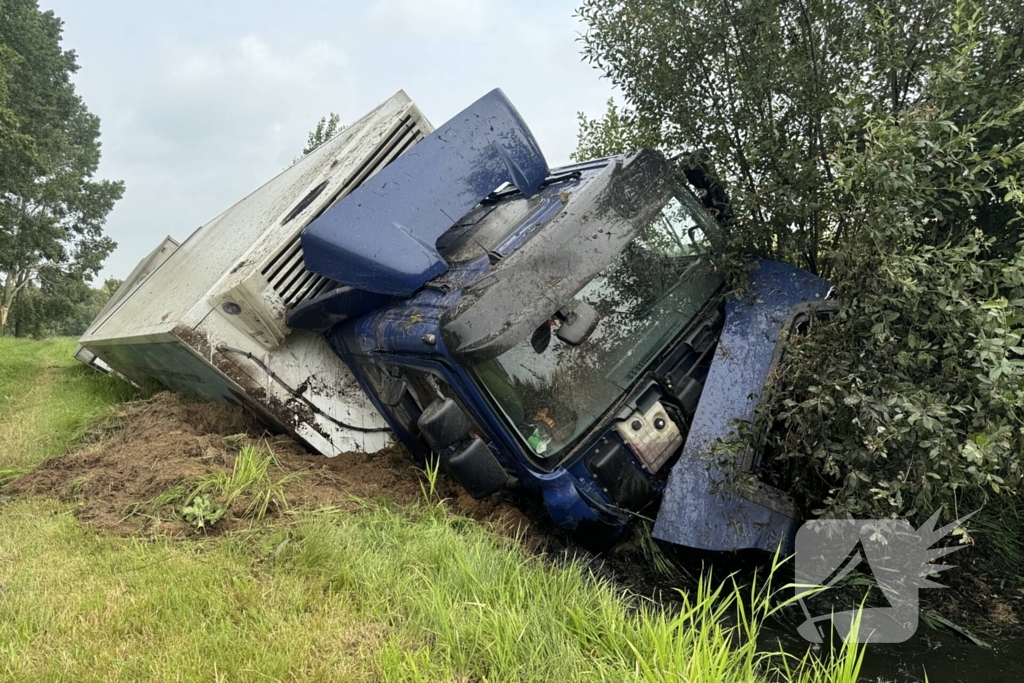 Vrachtwagen belandt in sloot naast snelweg, chauffeur ongedeerd