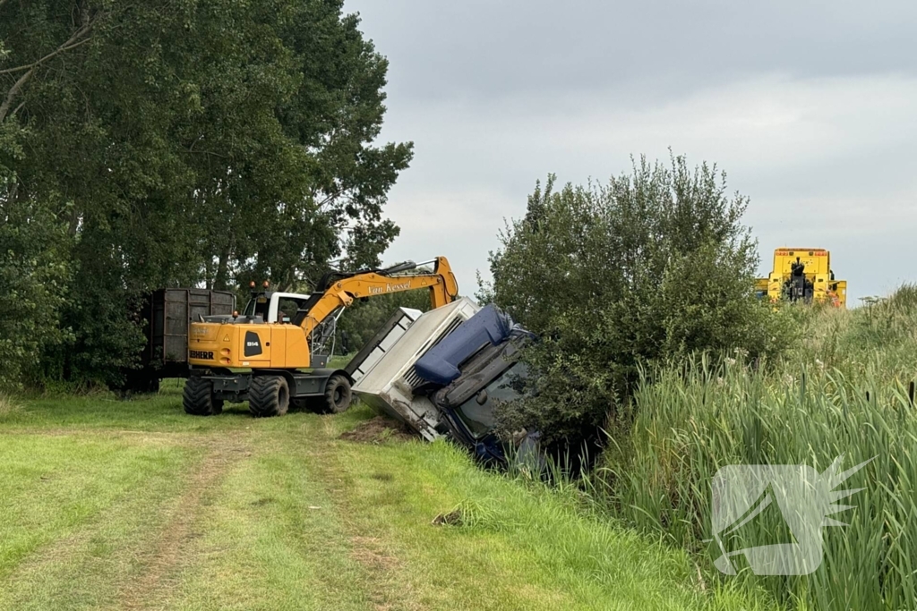 Vrachtwagen belandt in sloot naast snelweg, chauffeur ongedeerd