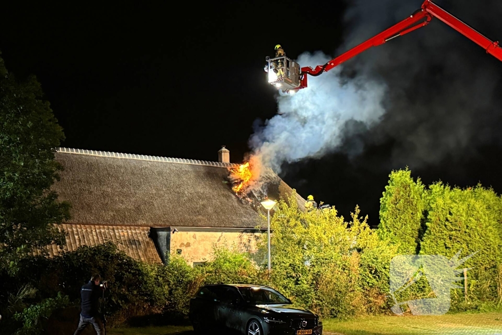 Vlammen slaan uit rietendak van woning