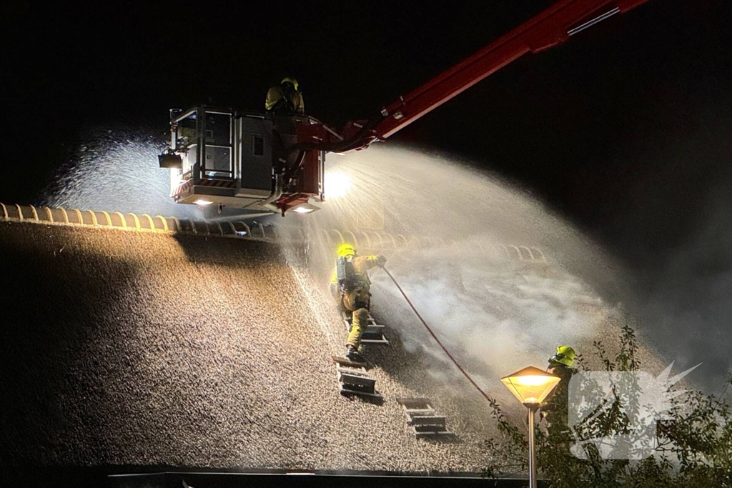 Vlammen slaan uit rietendak van woning