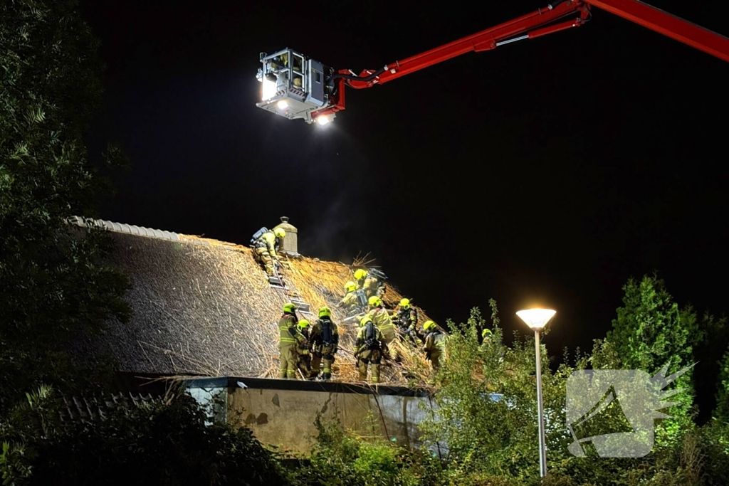 Vlammen slaan uit rietendak van woning