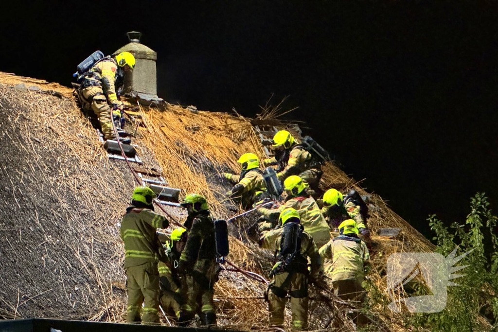 Vlammen slaan uit rietendak van woning