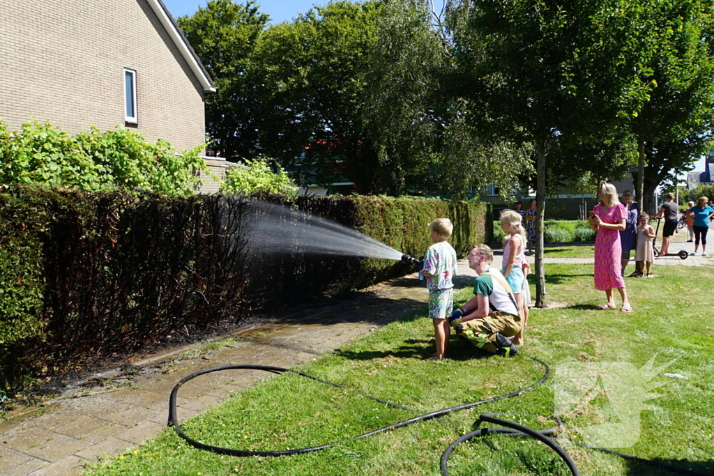 Kinderen blussen met brandweer brandende coniferenhaag