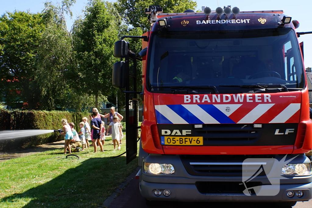 Kinderen blussen met brandweer brandende coniferenhaag