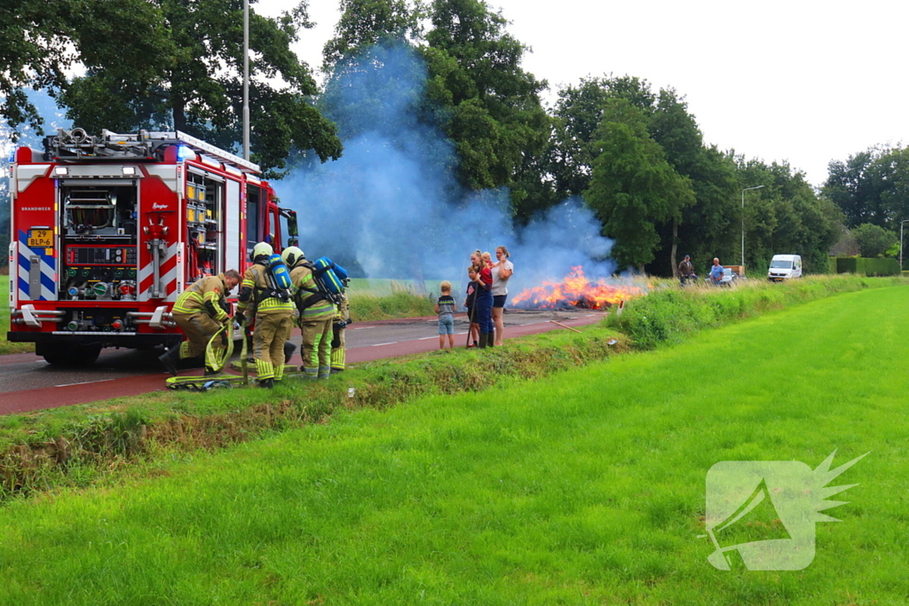 Brandweer blust brandend stro op aanhanger