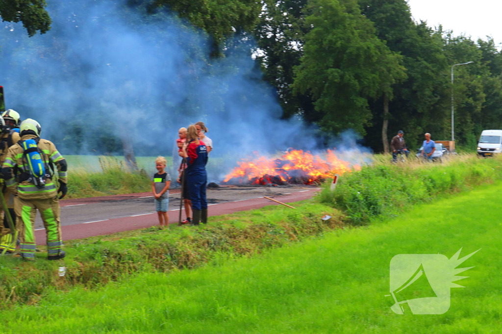 Brandweer blust brandend stro op aanhanger