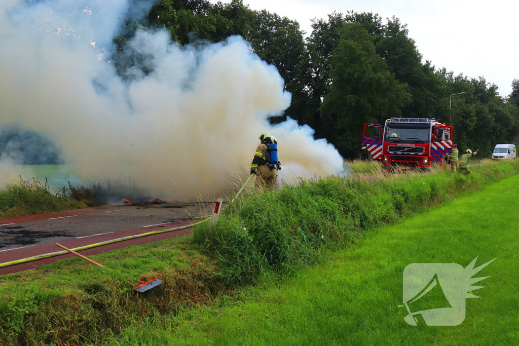 Brandweer blust brandend stro op aanhanger