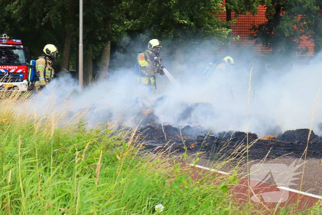 Brandweer blust brandend stro op aanhanger