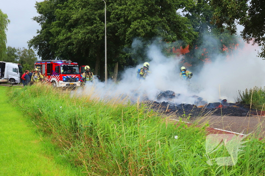 Brandweer blust brandend stro op aanhanger