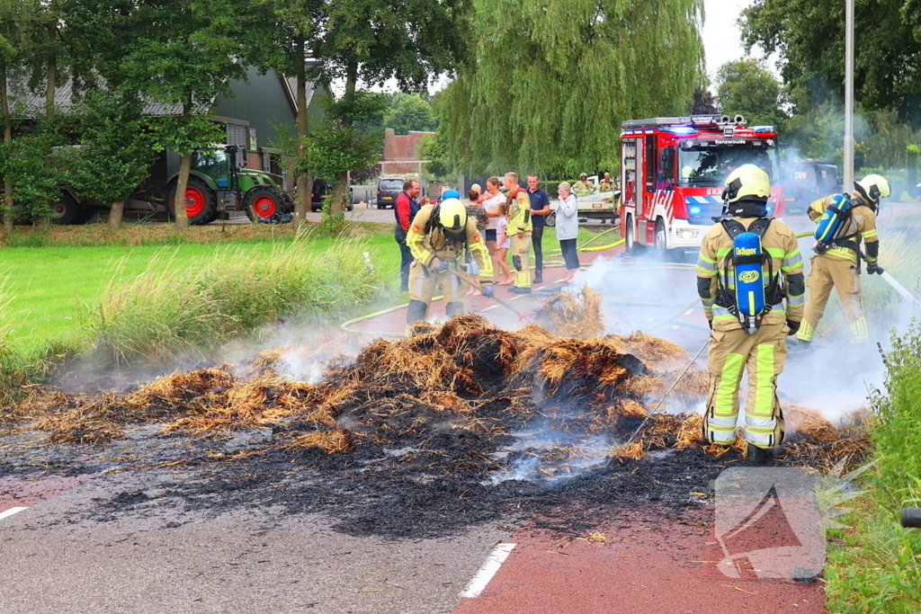 Brandweer blust brandend stro op aanhanger