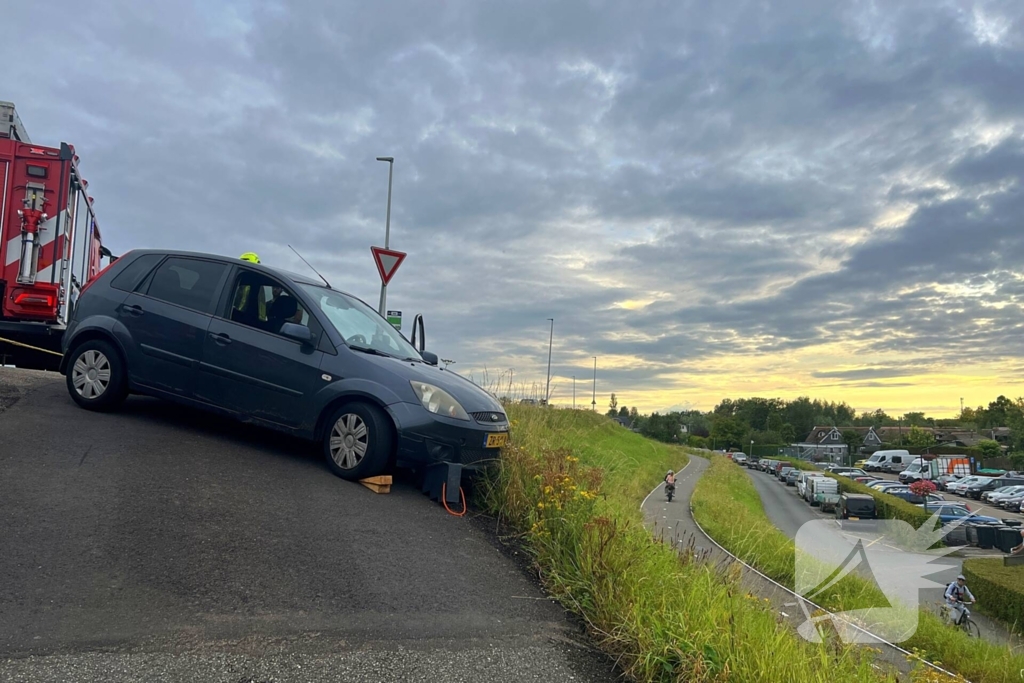 Brandweer trekt auto terug de dijk op