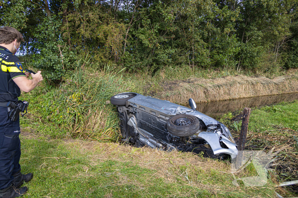 Omstanders halen automobilist uit te water geraakte auto