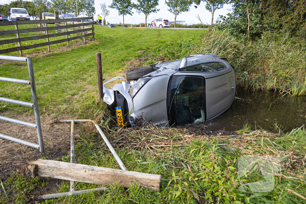 Omstanders halen automobilist uit te water geraakte auto