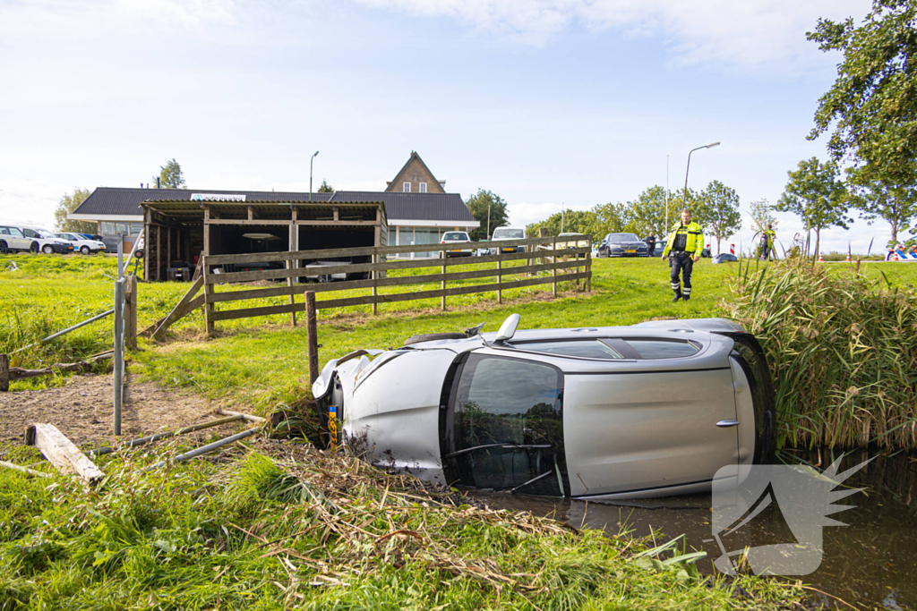 Omstanders halen automobilist uit te water geraakte auto