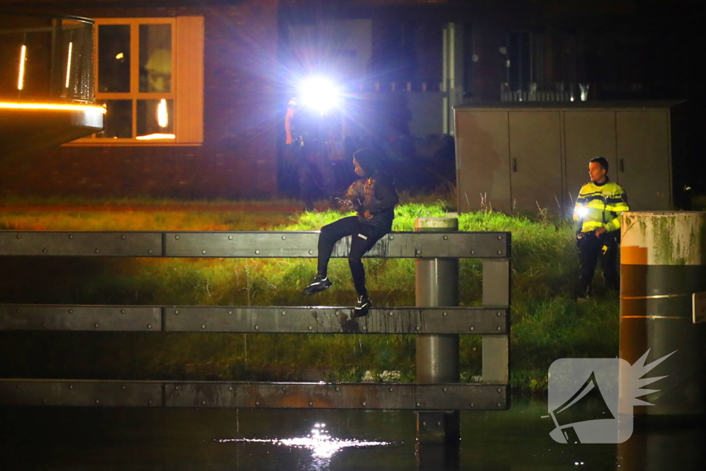 Persoon klimt op palen onder brug en word gebeten door politiehond