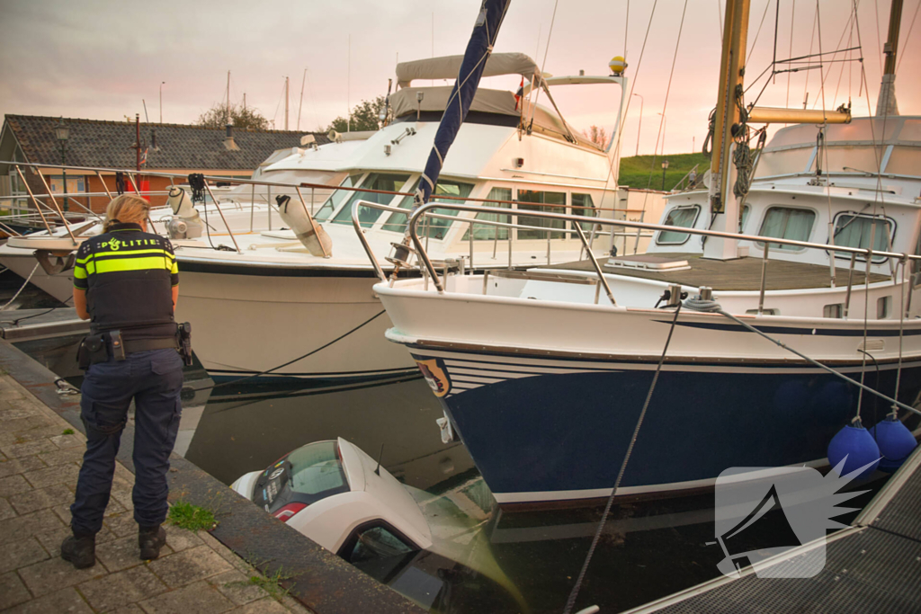 Auto rolt jachthaven in en gaat kopje onder