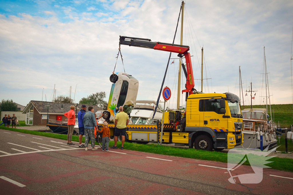 Auto rolt jachthaven in en gaat kopje onder