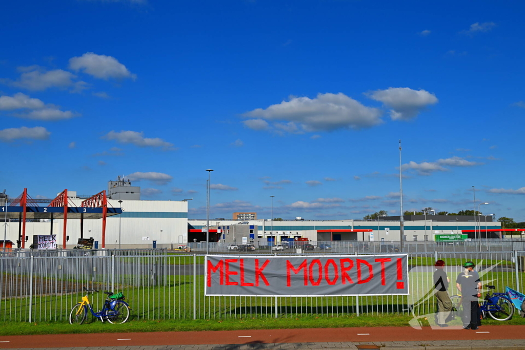 Demonstranten klimmen over hekken van zuivel fabrikant