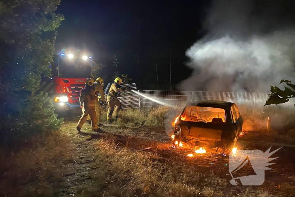 Brandweer blust brandende auto in bosgebied