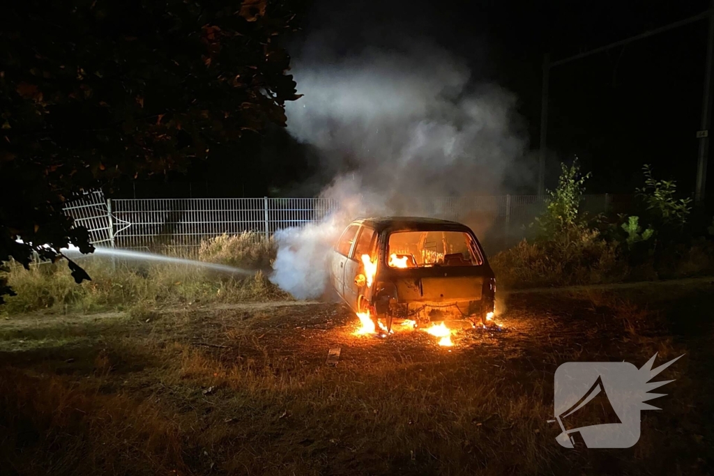 Brandweer blust brandende auto in bosgebied