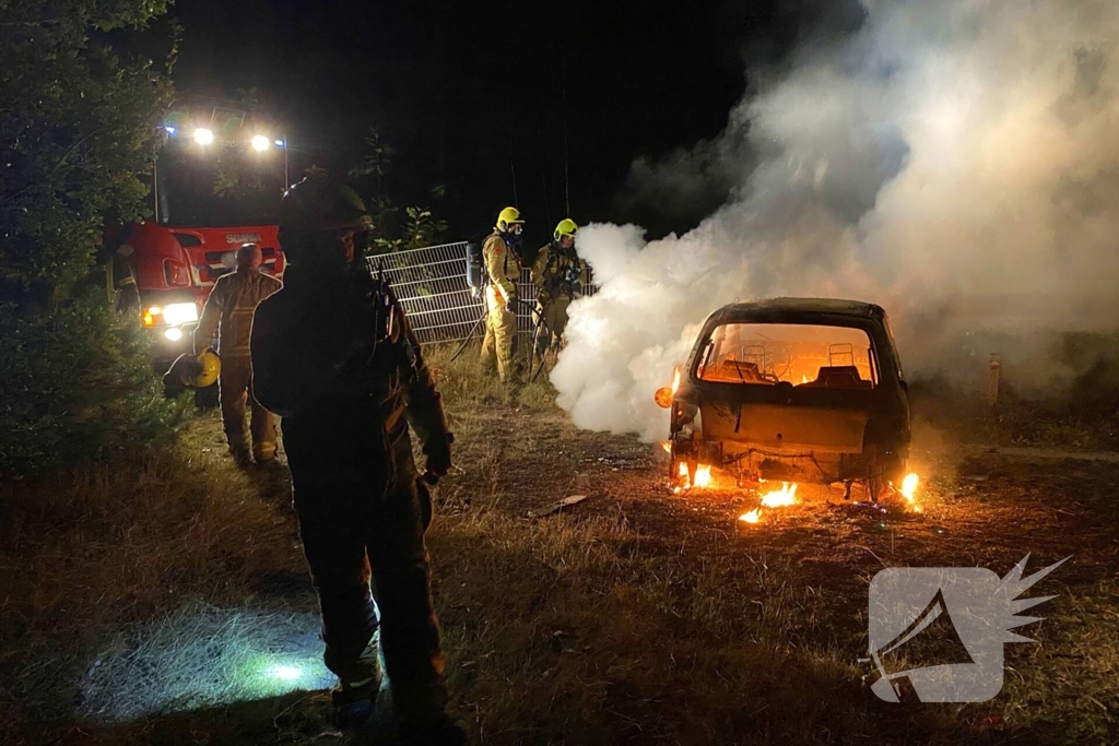 Brandweer blust brandende auto in bosgebied