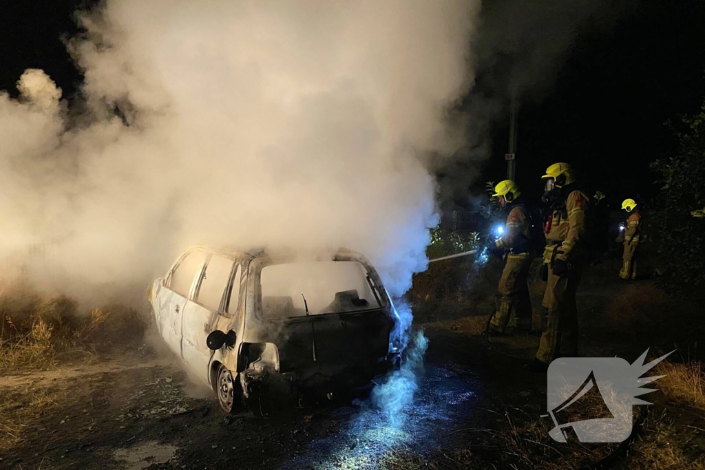 Brandweer blust brandende auto in bosgebied