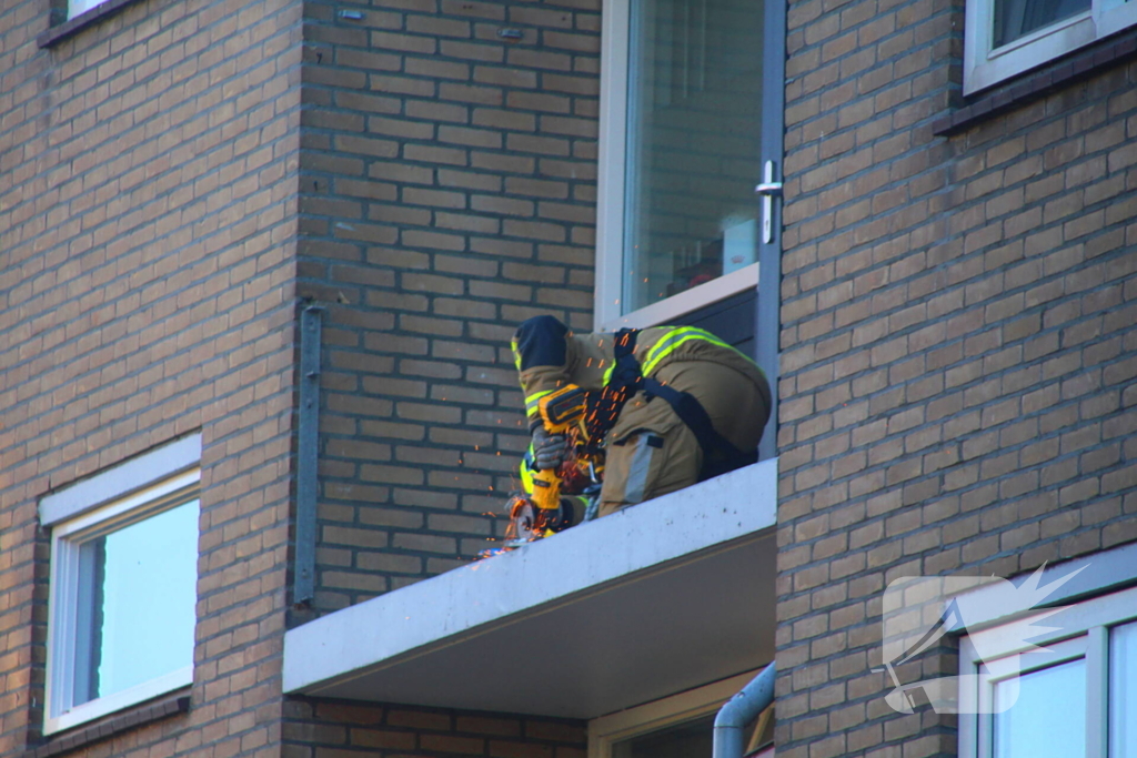 Persoon door hijskraan uit flatwoning getakeld