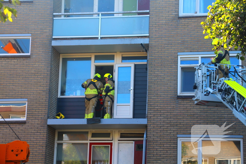 Persoon door hijskraan uit flatwoning getakeld