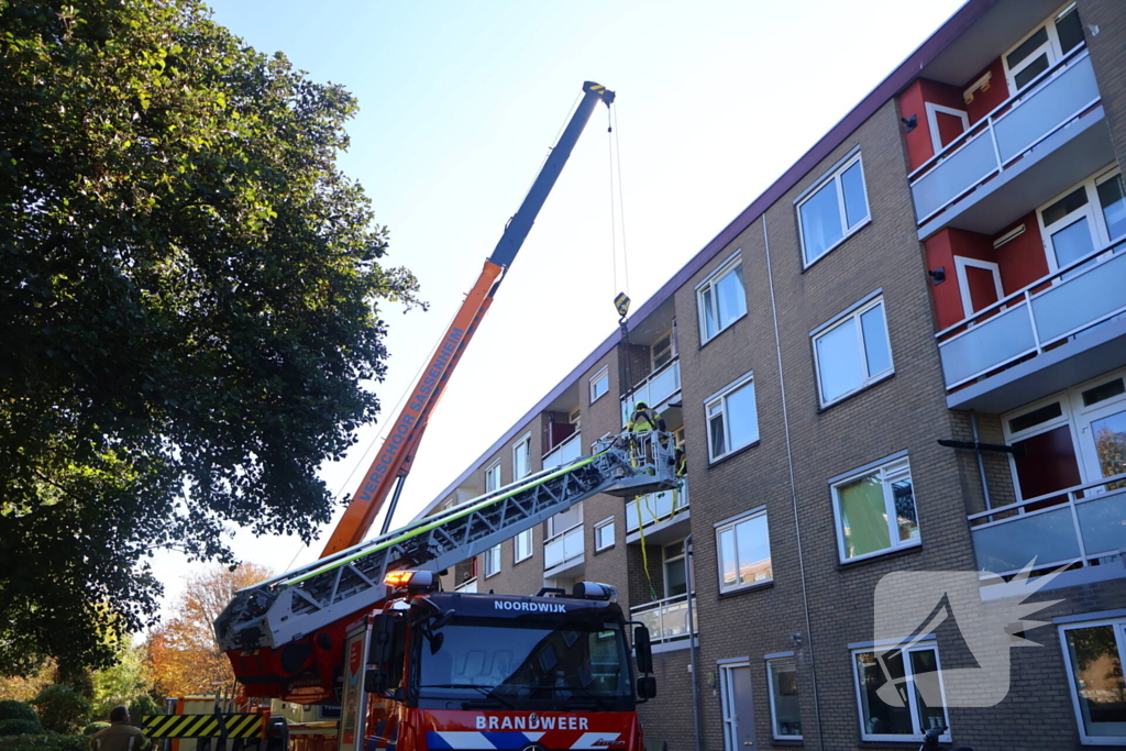 Persoon door hijskraan uit flatwoning getakeld