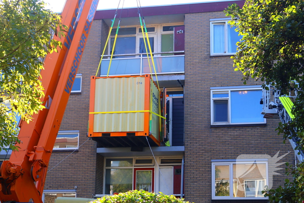 Persoon door hijskraan uit flatwoning getakeld