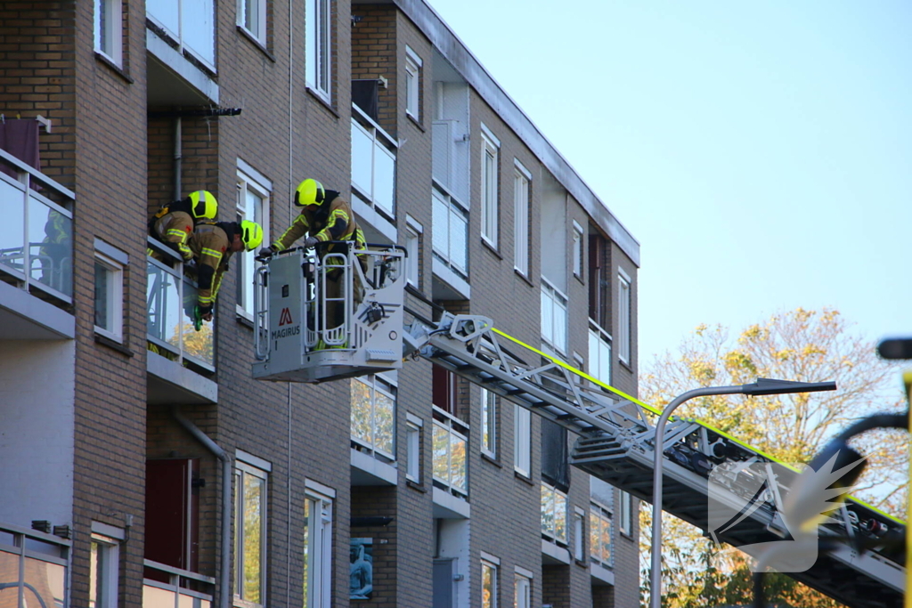 Persoon door hijskraan uit flatwoning getakeld