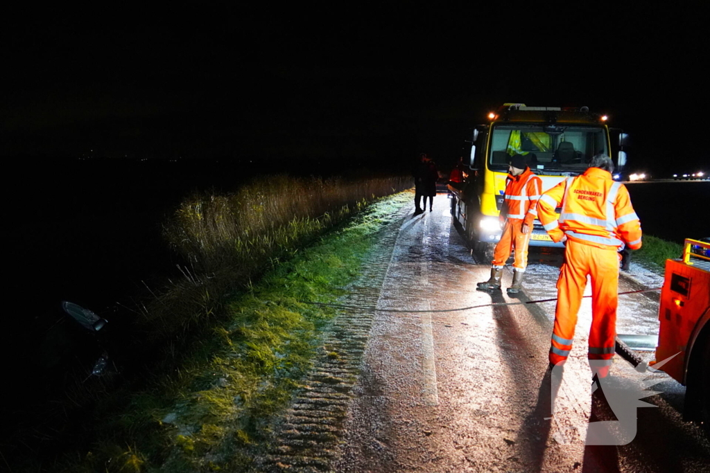 Twee auto's te water in bocht op gladde dijk