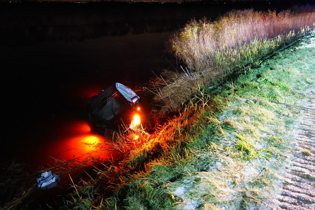 Twee auto's te water in bocht op gladde dijk