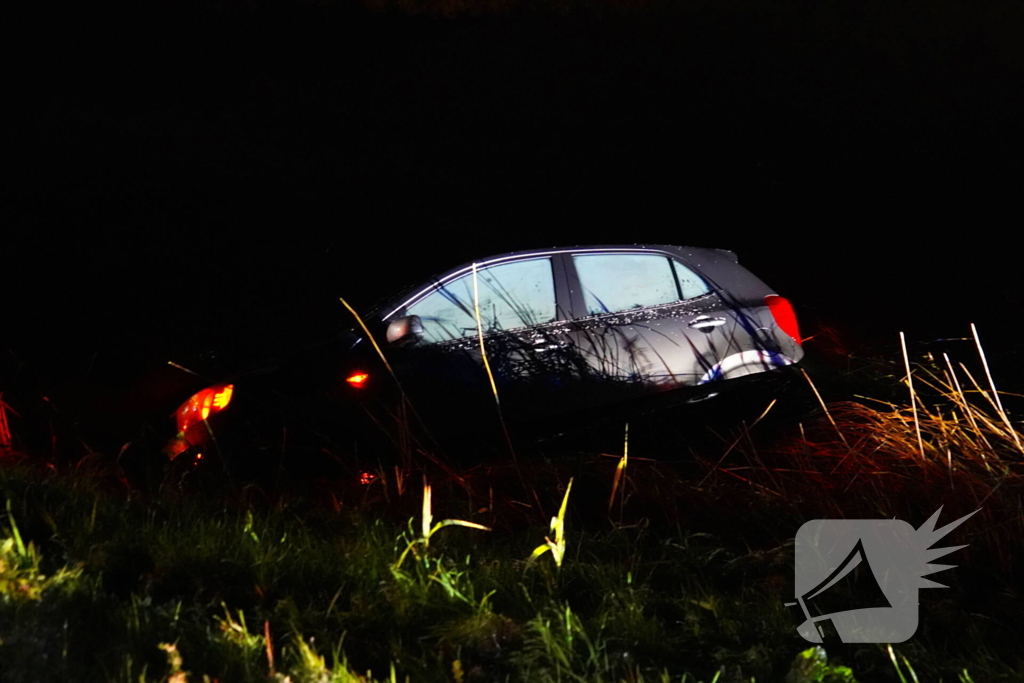 Twee auto's te water in bocht op gladde dijk