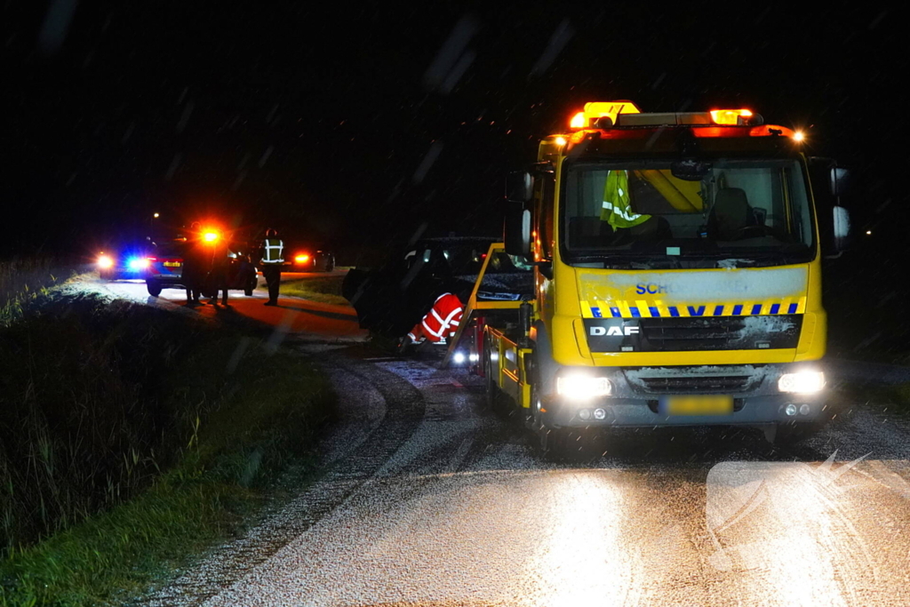 Twee auto's te water in bocht op gladde dijk