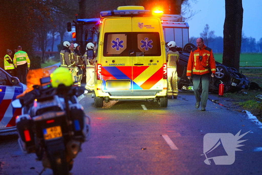 Auto op de kop na botsing met trekker en boom