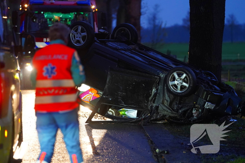 Auto op de kop na botsing met trekker en boom