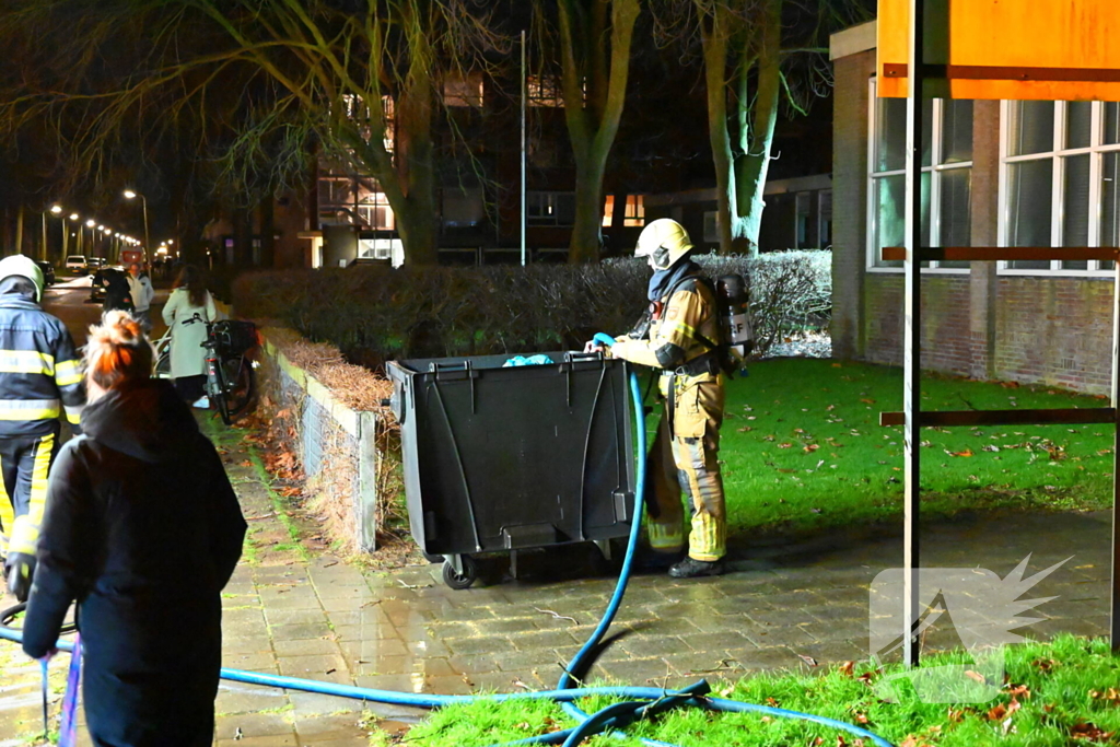 Brandweer blust brand in vuilcontainer