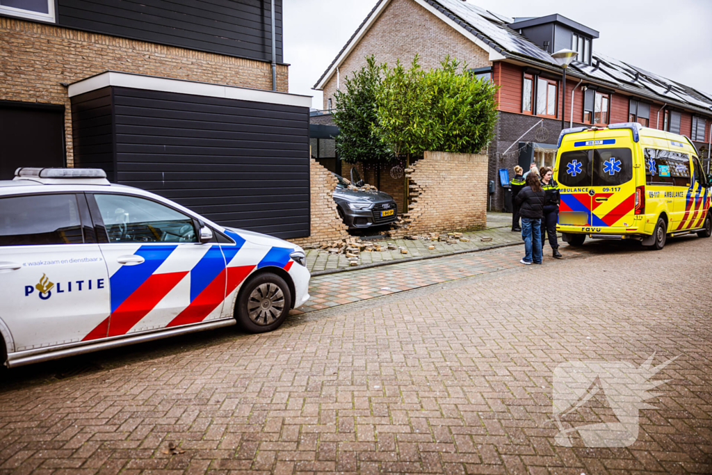 Auto rijdt dwars door tuinmuur