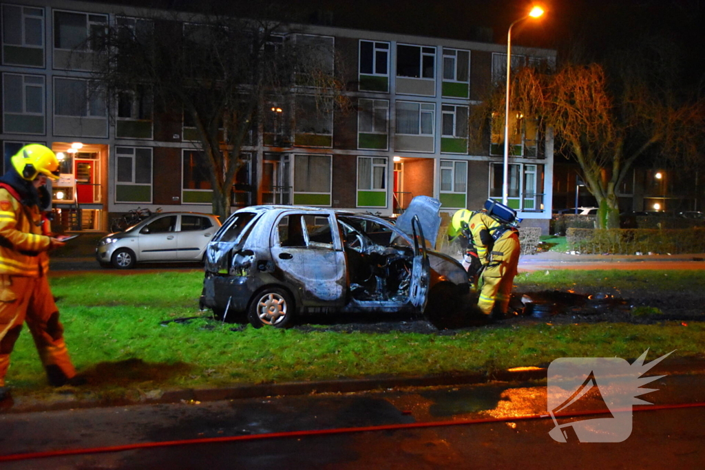 Auto in brand gestoken op grasveld