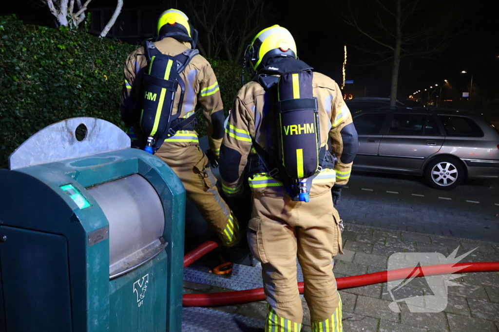 Personen verrichten bluspoging bij containerbrand