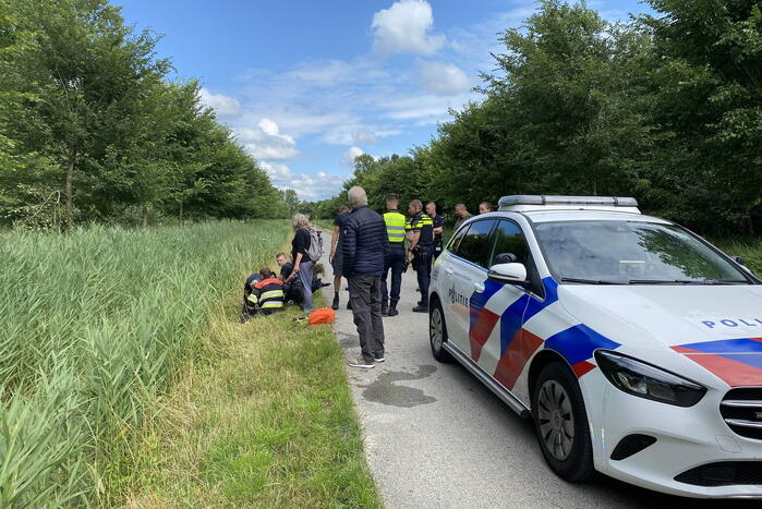 Vrouw rijdt met driewieler de sloot