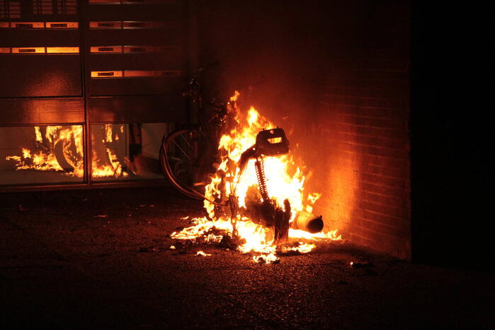 Brandweer blust brandende scooter tegen appartementencomplex