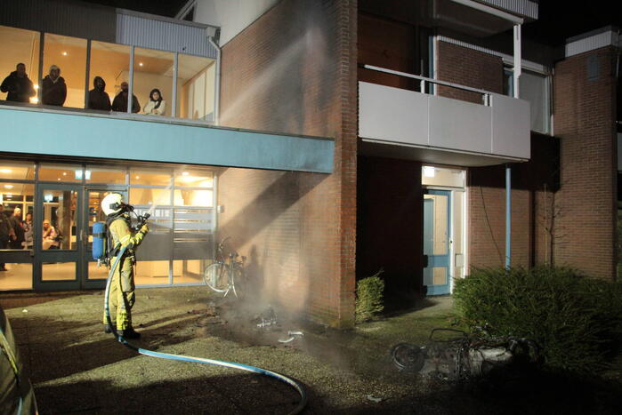 Brandweer blust brandende scooter tegen appartementencomplex