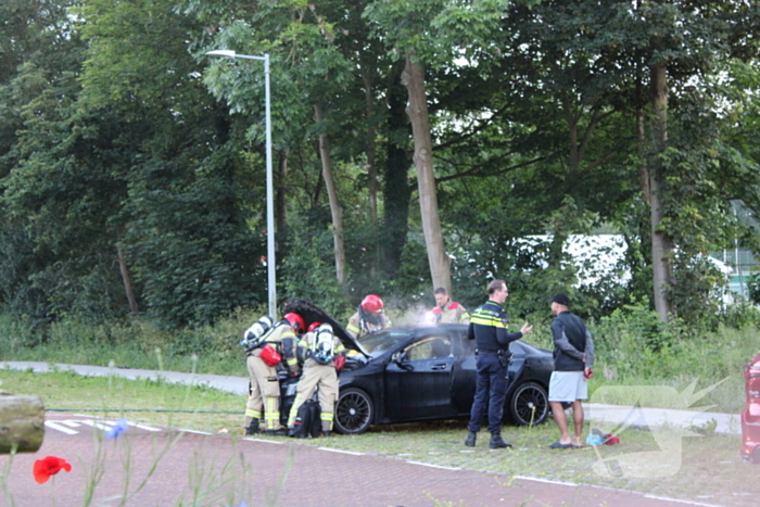 Brandweer blust brand in geparkeerde auto