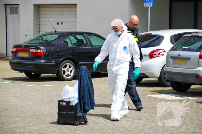 Forensisch onderzoek op parkeerplaats naast flatgebouw