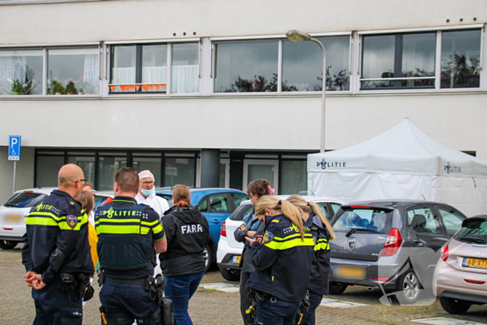 Forensisch onderzoek op parkeerplaats naast flatgebouw