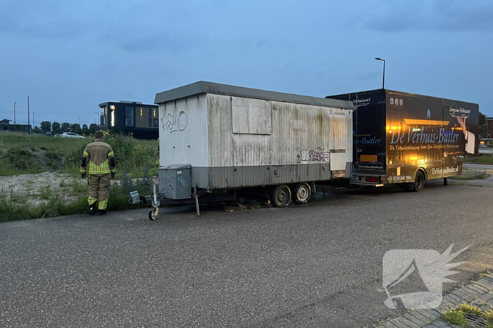 Brandweer blust in brand gestoken bouwkeet vol rommel