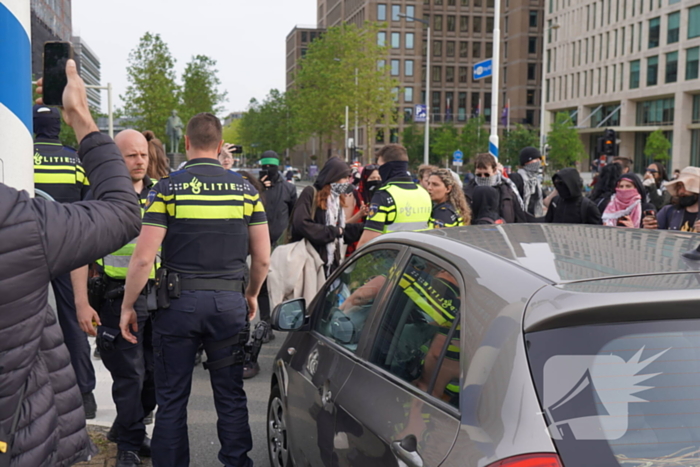 Demonstranten trekken persoon van scooter en slaan op auto's